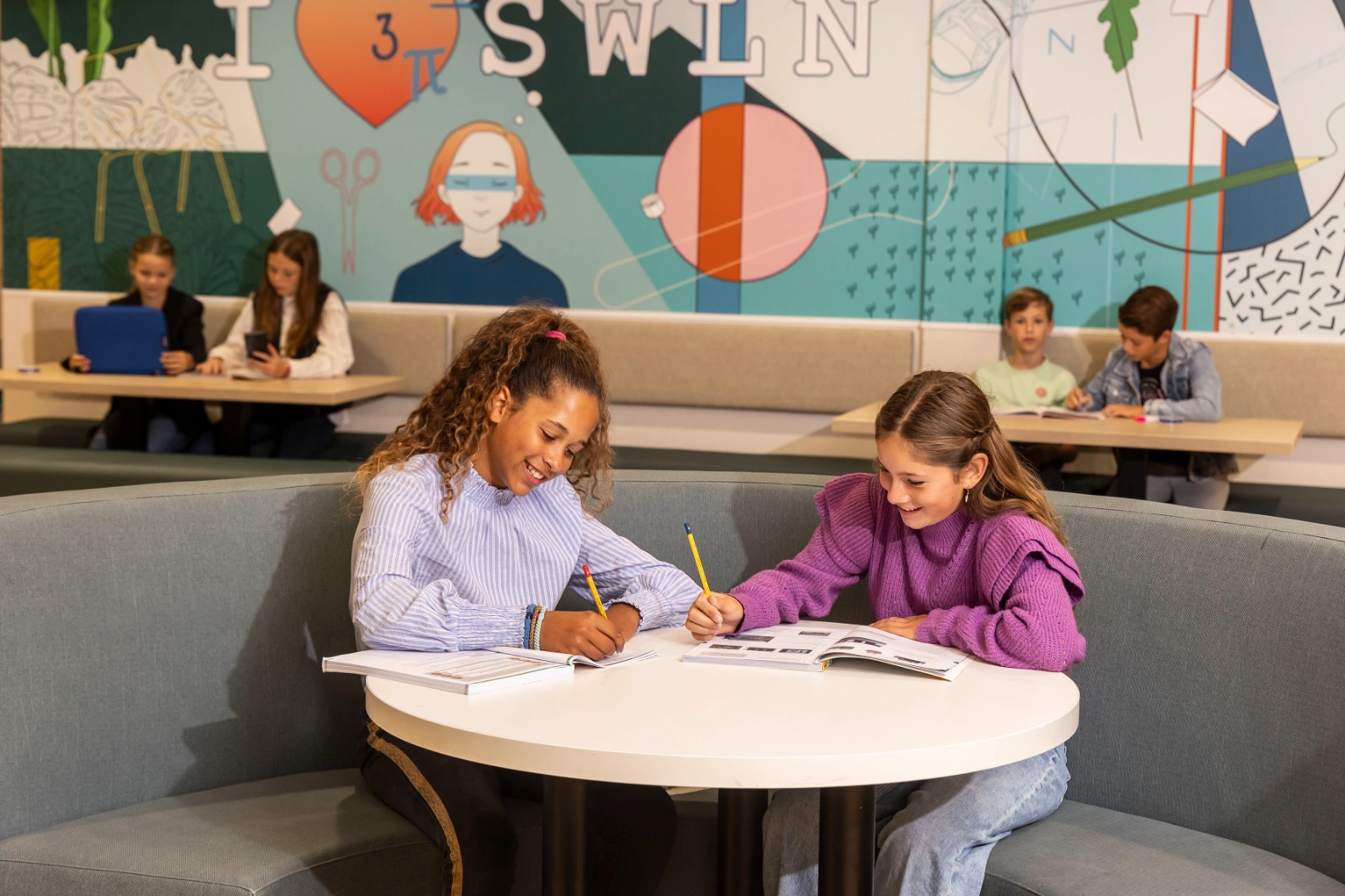 Leerlingen van ISW Sweelincklaan werken samen in de studieruimte met een grote kleurrijke wand
